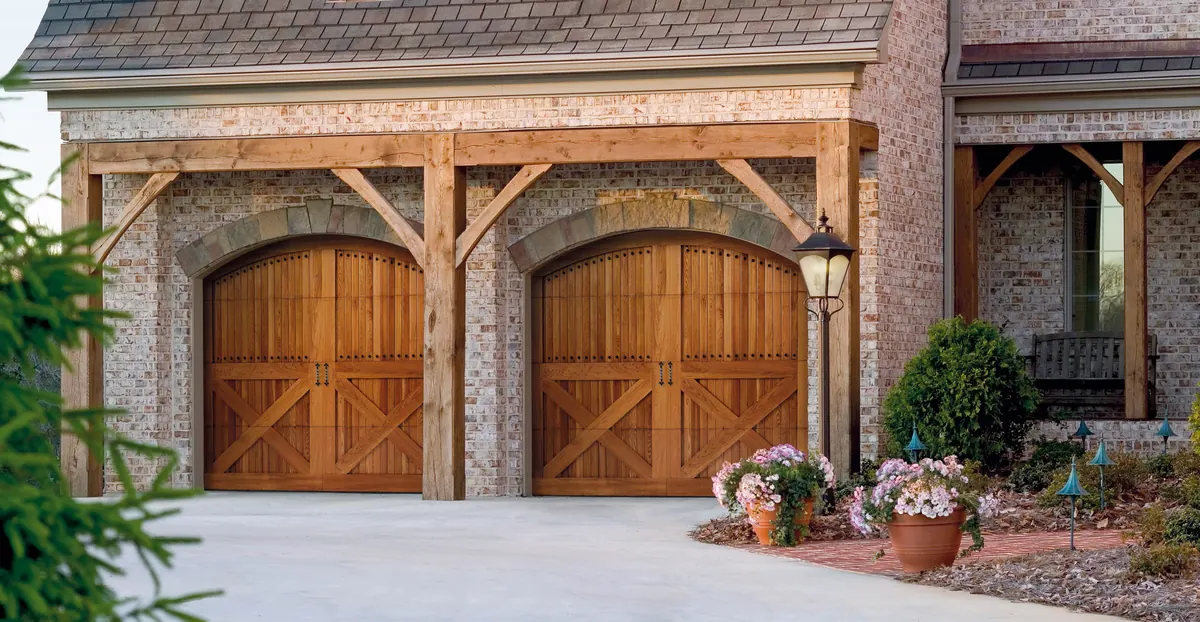 Amarr By Design handcrafted wood carriage doors with arched tops under a timber porch