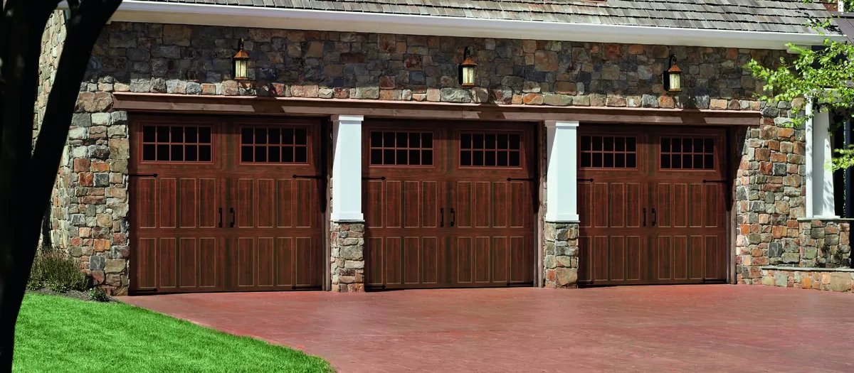 Three dark Amarr Classica carriage doors on a stone three car garage