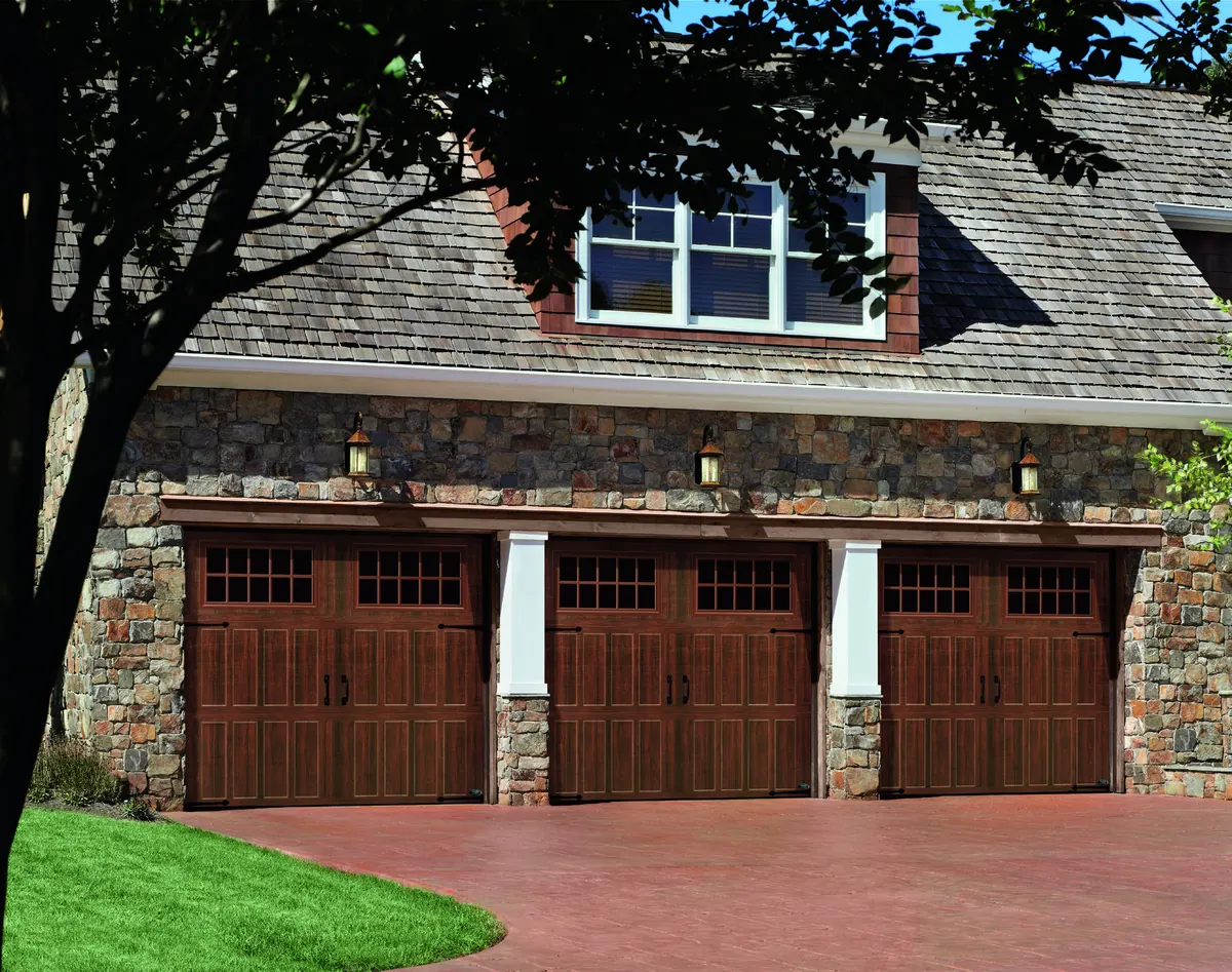 Amarr Classica doors in dark walnut on a stone three car garage