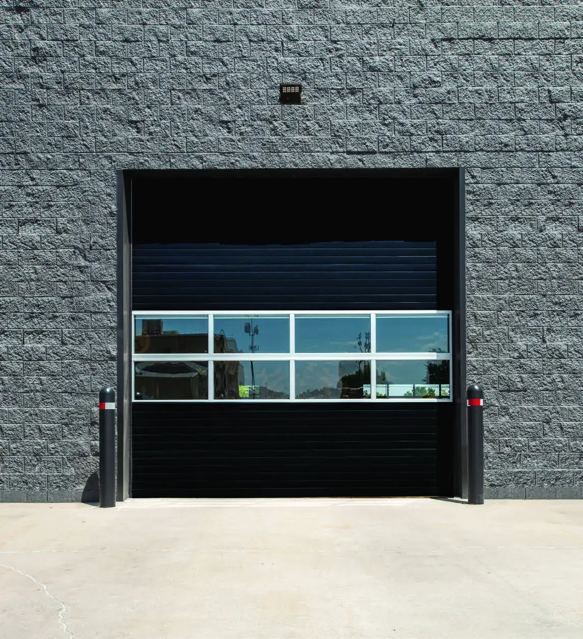Black Amarr 2432 series commercial door with a full view glass section on a block building