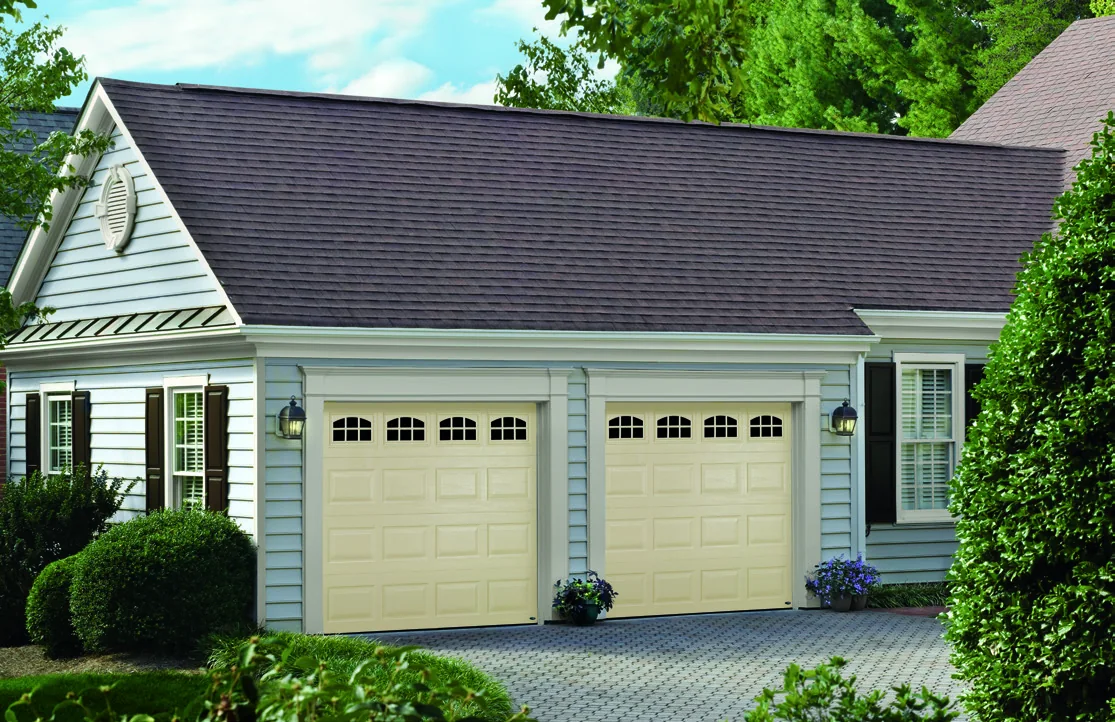 Three cream garage doors with window sections on a colonial style home