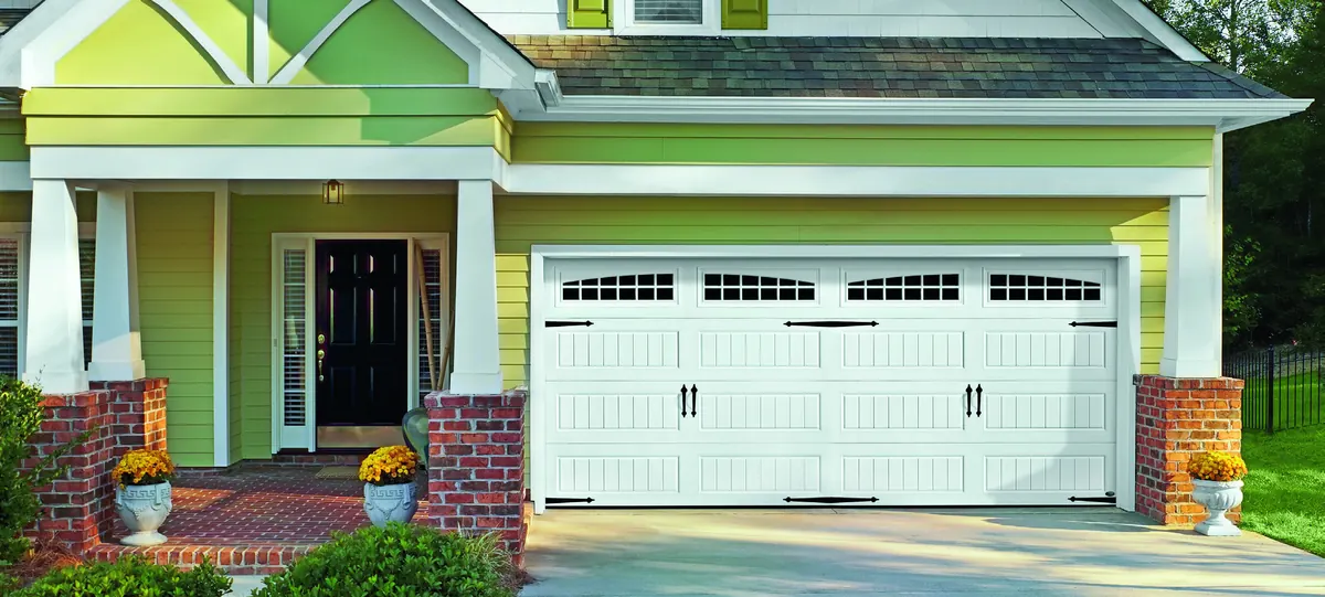 White Amarr Heritage carriage style doors with windows on a stone home