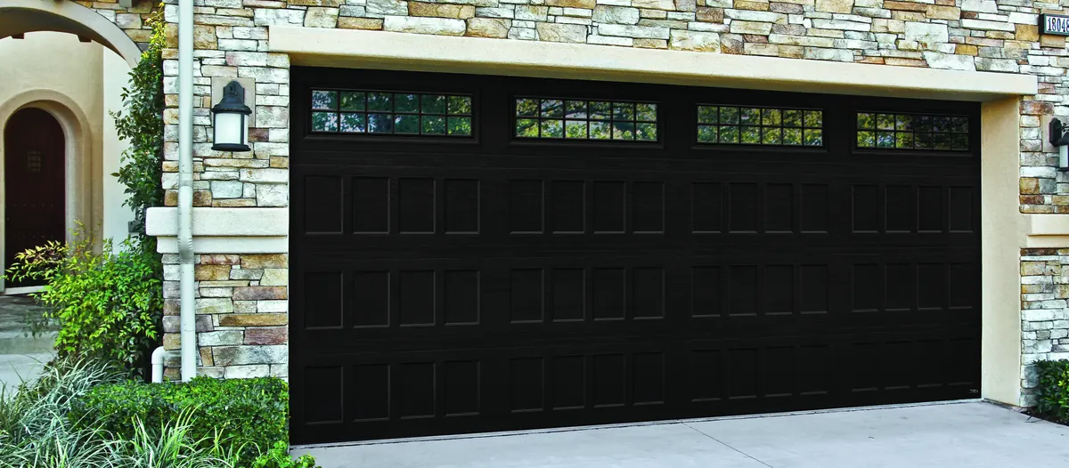 Pair of white Amarr Hillcrest carriage doors with arched windows on a grey home