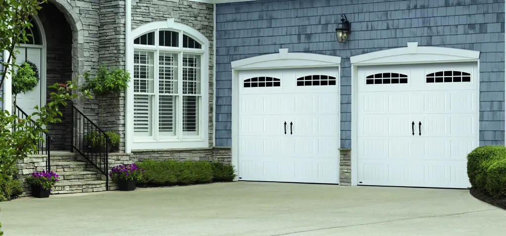 Two white Amarr Hillcrest carriage doors on a stone home