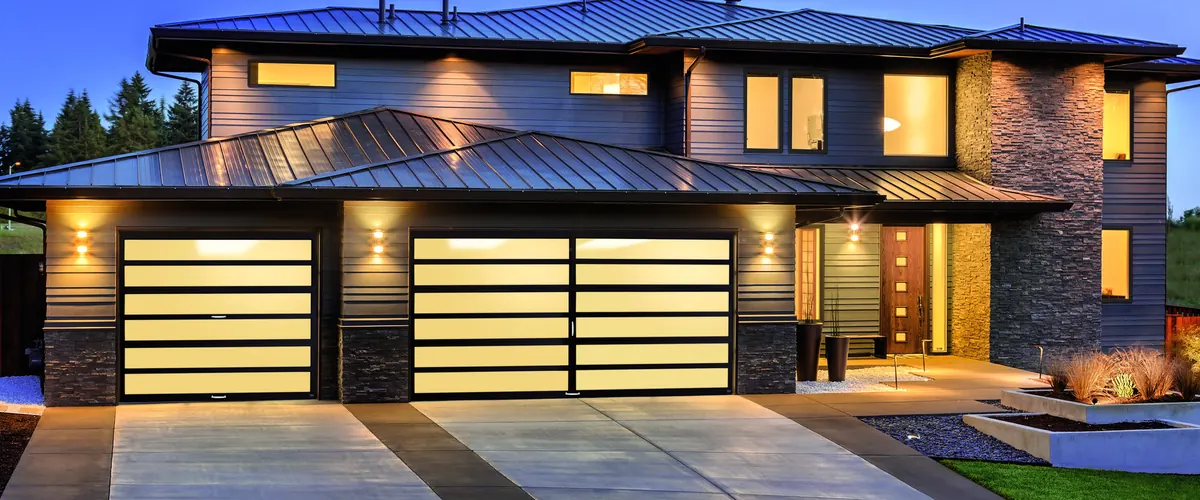 Amarr Horizon full view aluminum doors lit from inside on a modern home at dusk