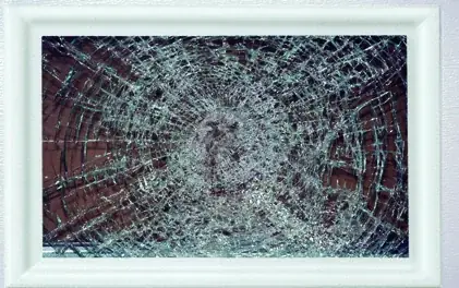 Garage door window glazing after a large missile impact test, cracked through but still held in its frame