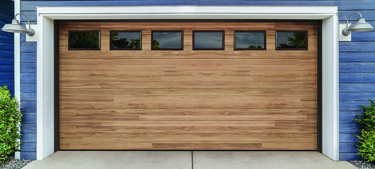 Amarr Northwoods plank door in a light wood tone on a blue home