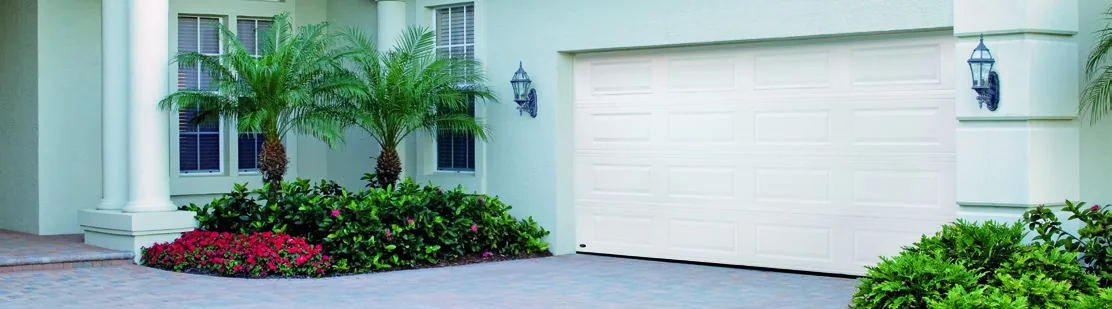 A white garage door on a palm lined South Florida driveway