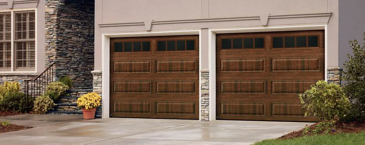 Amarr walnut wood look raised panel doors on a stone and stucco home