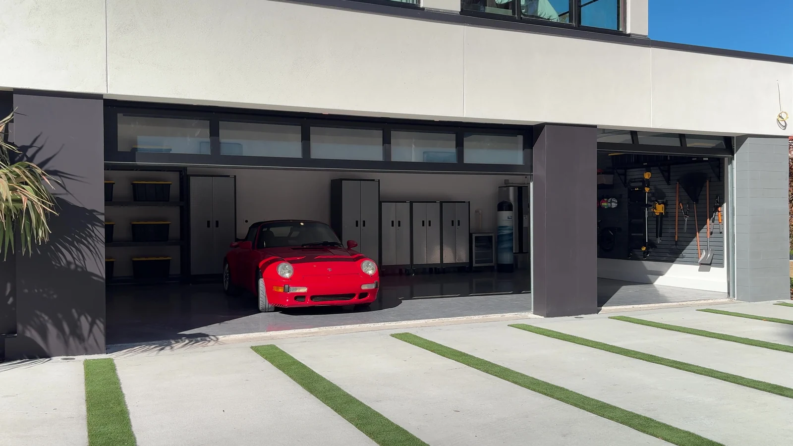 Full view glass garage door standing open on a bright day with a car parked inside