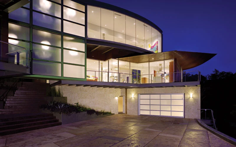 Full view glass garage door on a contemporary home lit at dusk