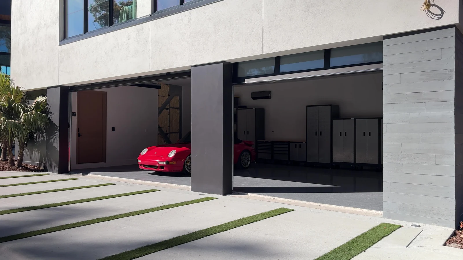 Full view glass garage doors open with a car parked in the bay