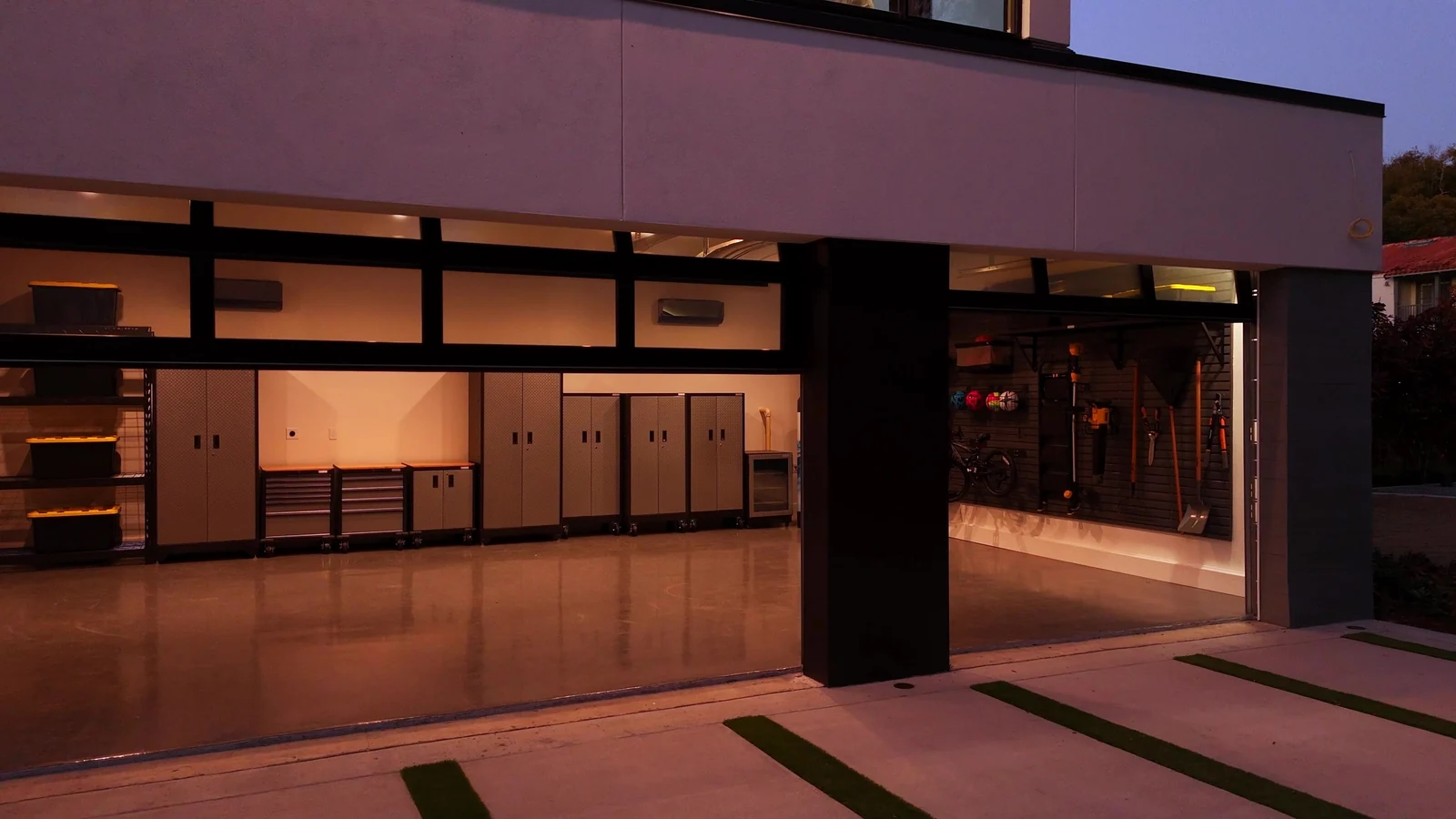Warm lit garage behind an open full view glass door at dusk