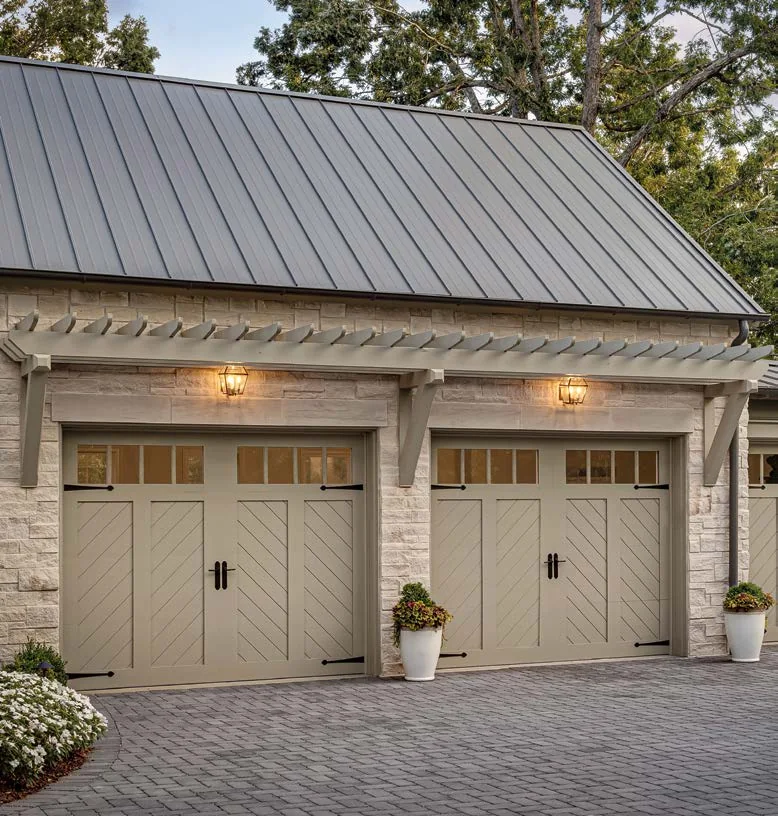 Two cream garage doors on a home with a standing seam metal roof