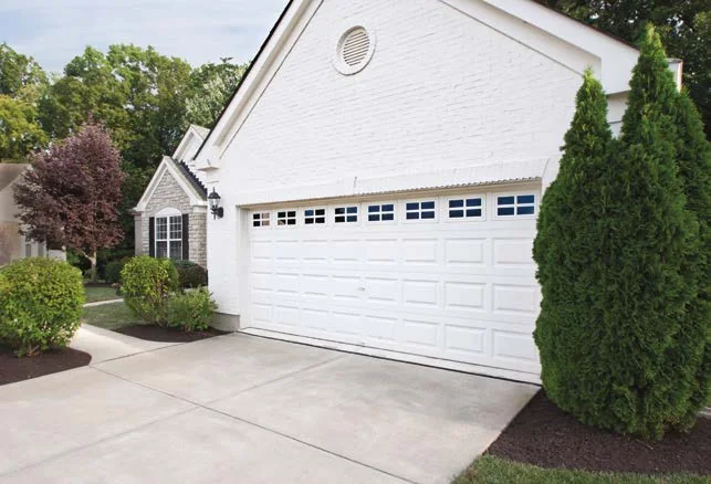 A white raised panel garage door on a light stucco home