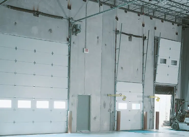 Amarr 2432 full view commercial door, white insulated steel dock doors with window rows inside a warehouse. From the 2432/2732 brochure