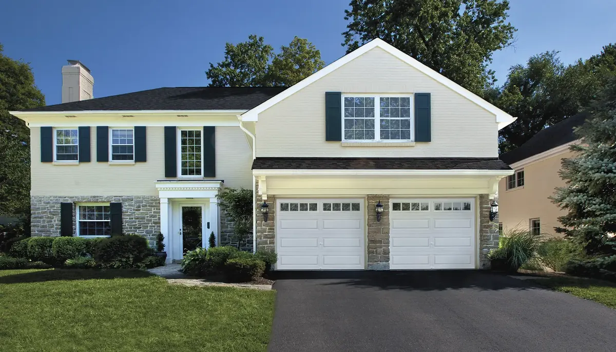 Clopay Classic garage door, classic Steel short panels with Colonial windows in white, pair on a cream house