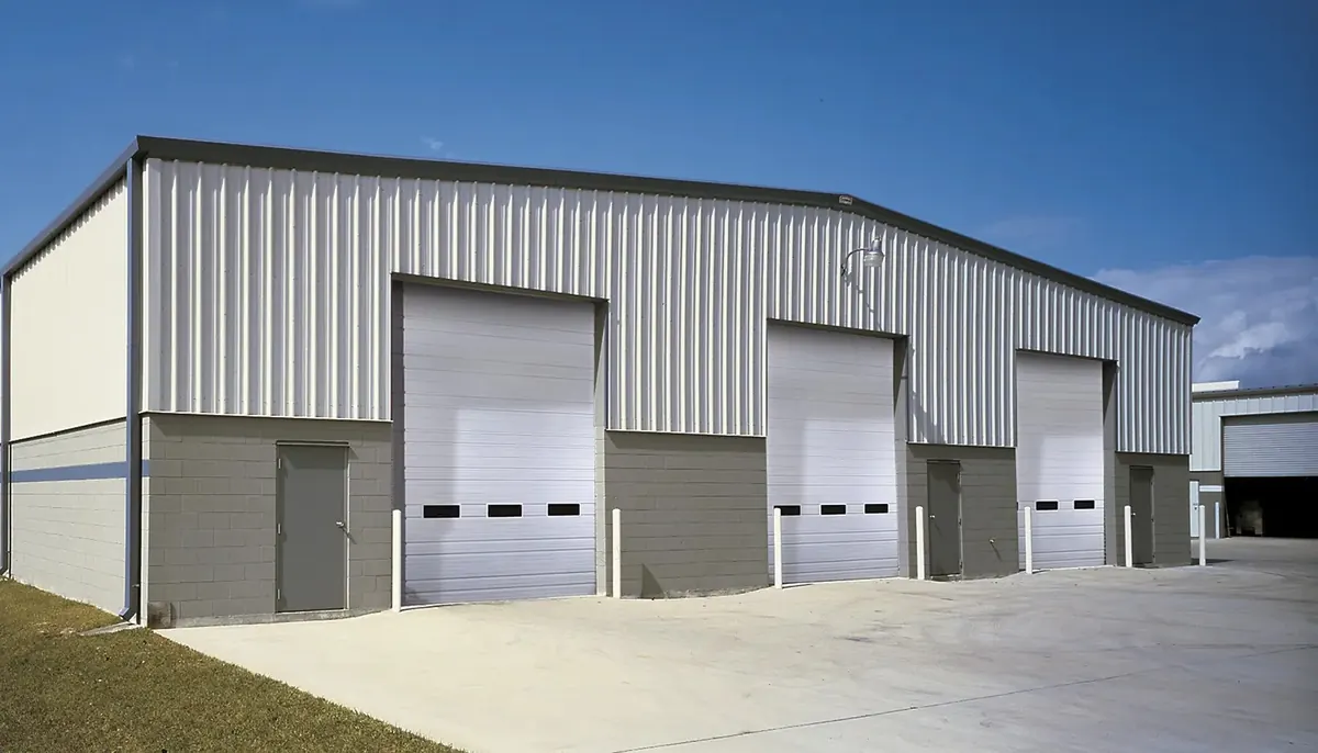 Clopay Industrial ribbed steel door, three white ribbed steel doors with a window row on a gray steel building