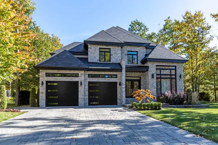 Raynor Aspen Contempra garage door, two black plank doors with slim windows on a stone home
