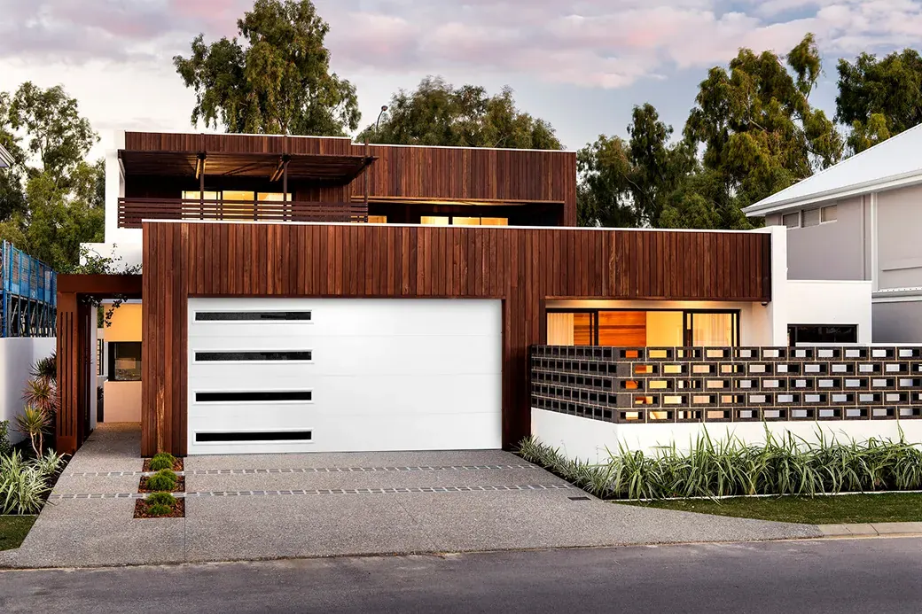 Puerta de garaje Raynor Aspen Contempra, puerta blanca lisa con ranuras de ventana largas y negras en una casa moderna revestida de madera