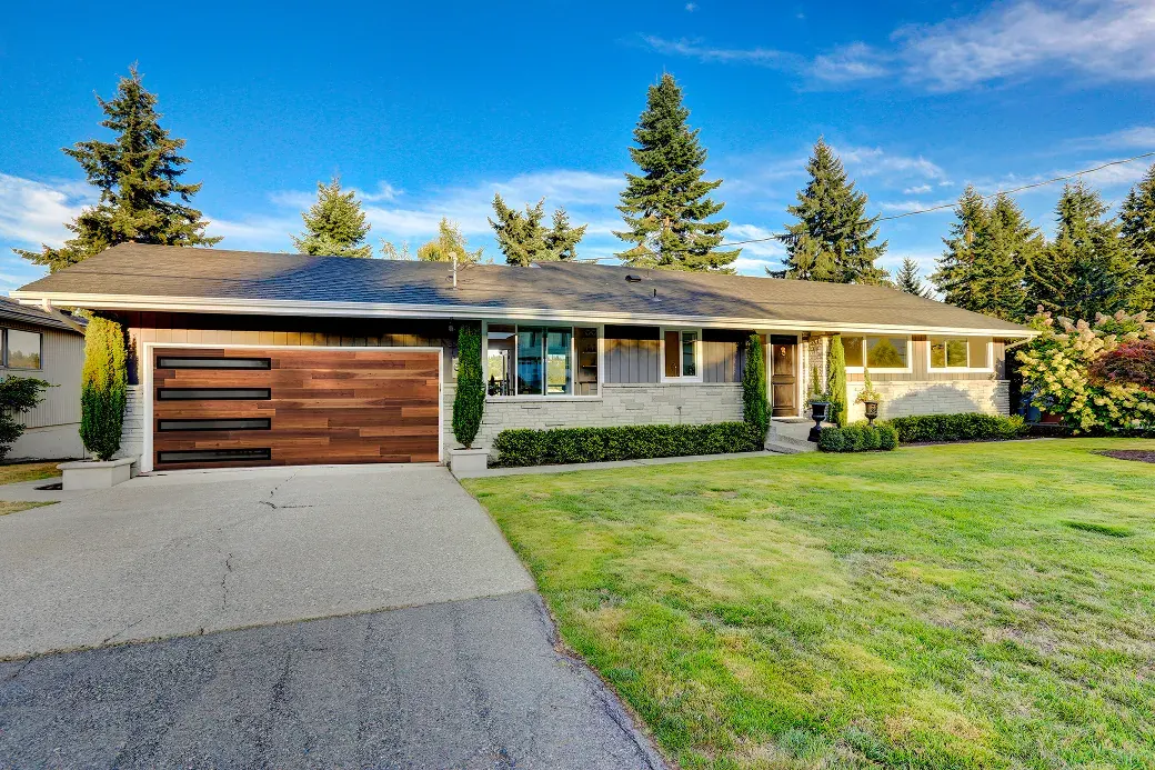 Puerta de garaje Raynor Aspen Contempra, puerta de tablón en tono madera en una casa tipo ranch