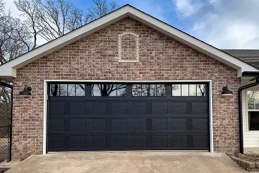 Puerta de garaje Raynor Country Manor, puerta negra con ventanas en un garaje de ladrillo con techo a dos aguas