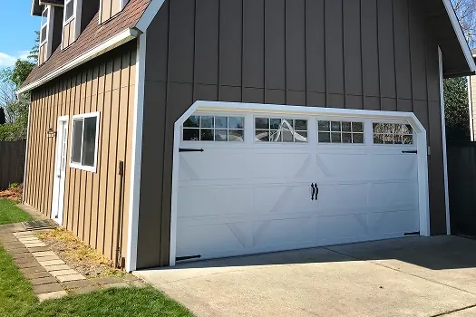 Puerta de garaje Raynor Country Manor, puerta blanca con ventanas en arco y manijas en una casa oscura de tablas verticales