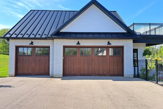 Puerta de garaje Raynor Revival Wood, dos puertas de madera estilo cochera en una casa blanca con techo metálico