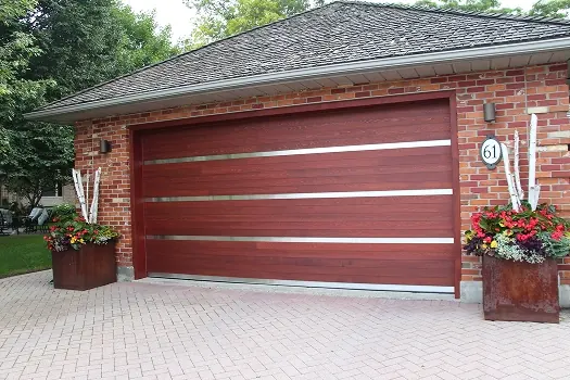 Puerta de garaje Raynor Revival Wood, puerta de madera roja con tablas horizontales y franjas metálicas en una casa de ladrillo