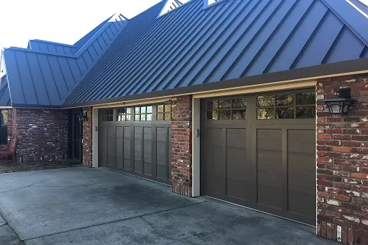 Puerta de garaje Raynor RockCreeke, dos puertas café oscuro estilo cochera con ventanas bajo un techo metálico
