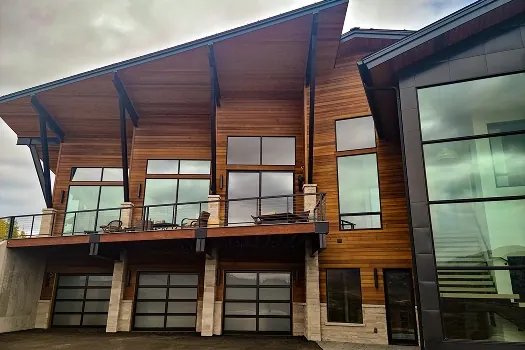 Puerta de garaje Raynor StyleView, tres puertas de vidrio bajo una casa moderna revestida de madera