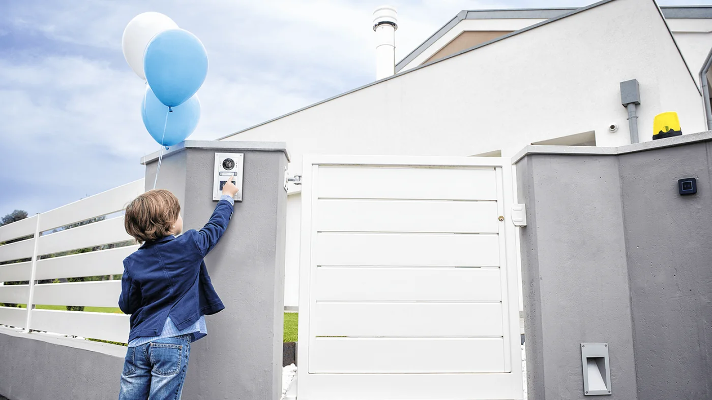 A child at a closed automatic gate, showing the safety photo eyes on the post