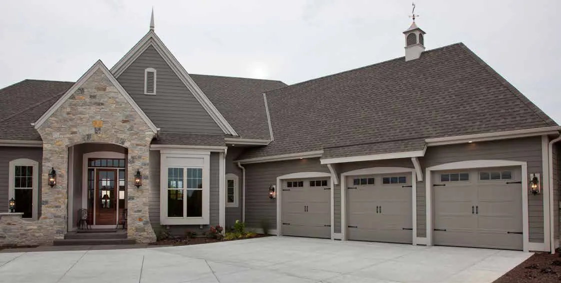 Grey Haas 5000 series carriage doors on a stone three car garage