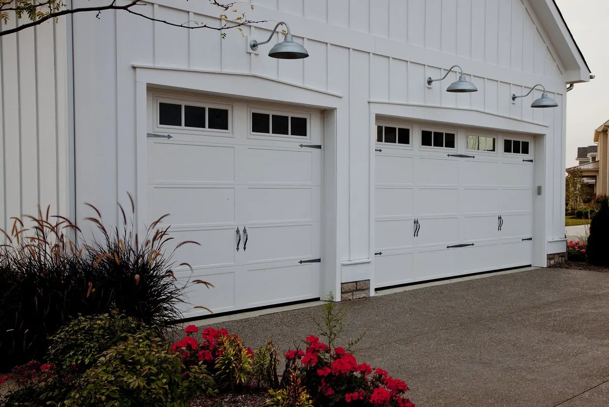 Two white Haas 600 series carriage style doors with windows on a white home