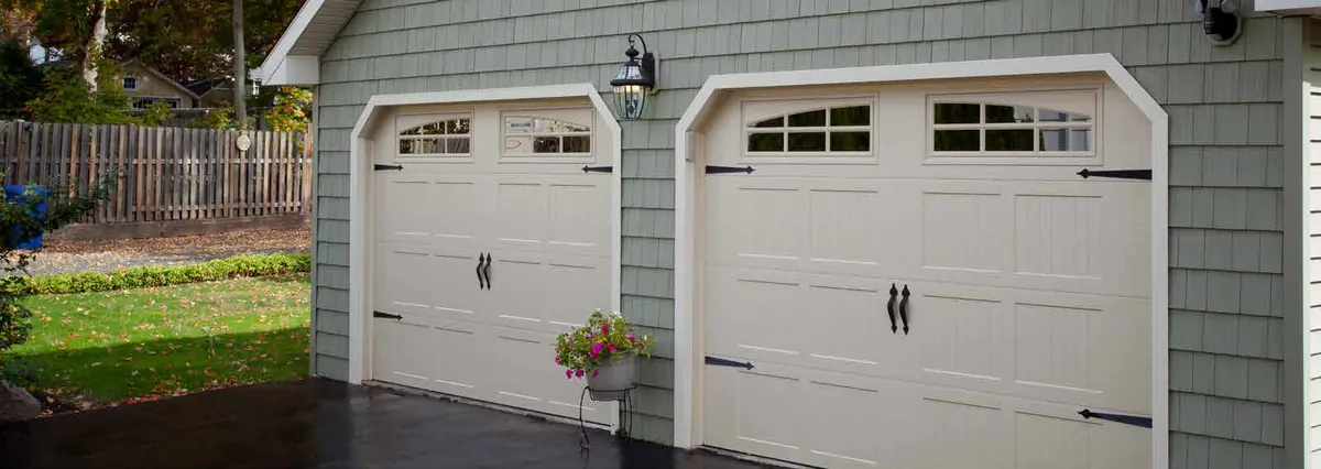 White Haas 700 series carriage doors with windows on a grey home
