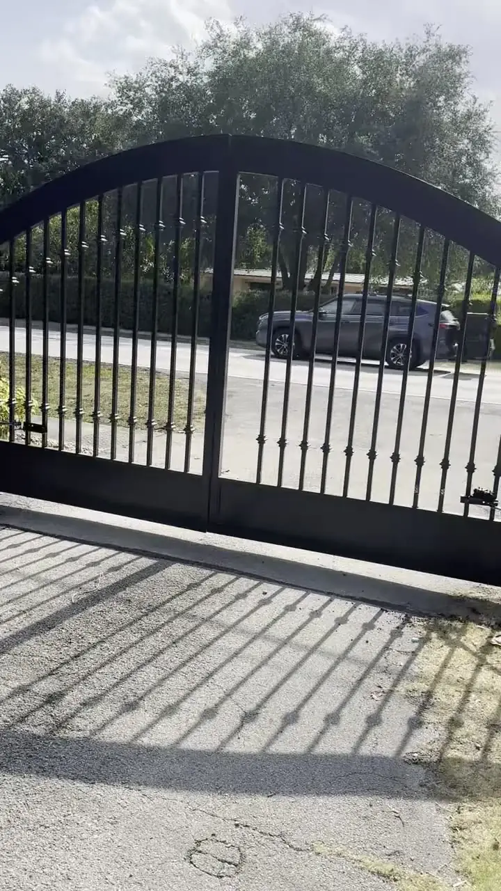 Arched ornamental driveway gate on brick piers at a completed CMC gate installation