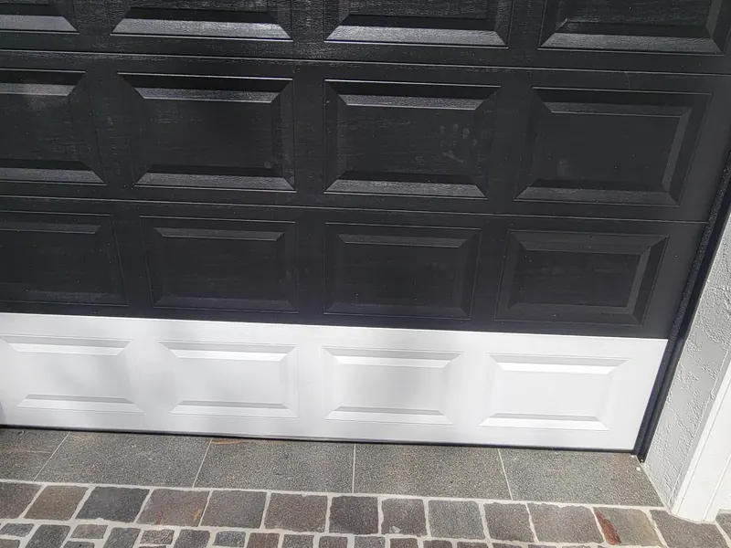 A cutaway of a garage door bottom seal seated against the floor