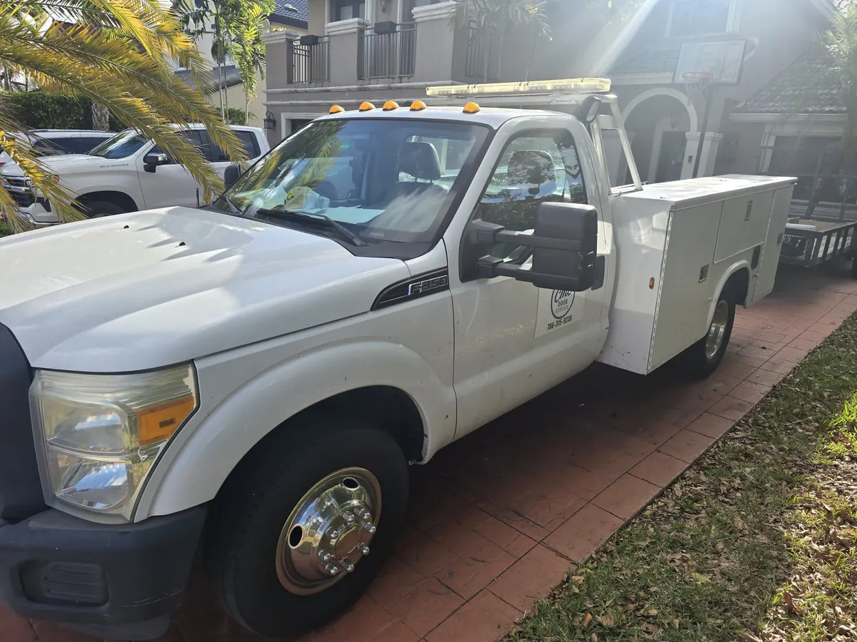 The CMC Door Service truck parked on a driveway with the ladder rack loaded and the service body closed