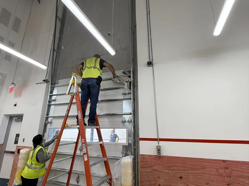 Equipo de CMC instalando una puerta seccional comercial gris