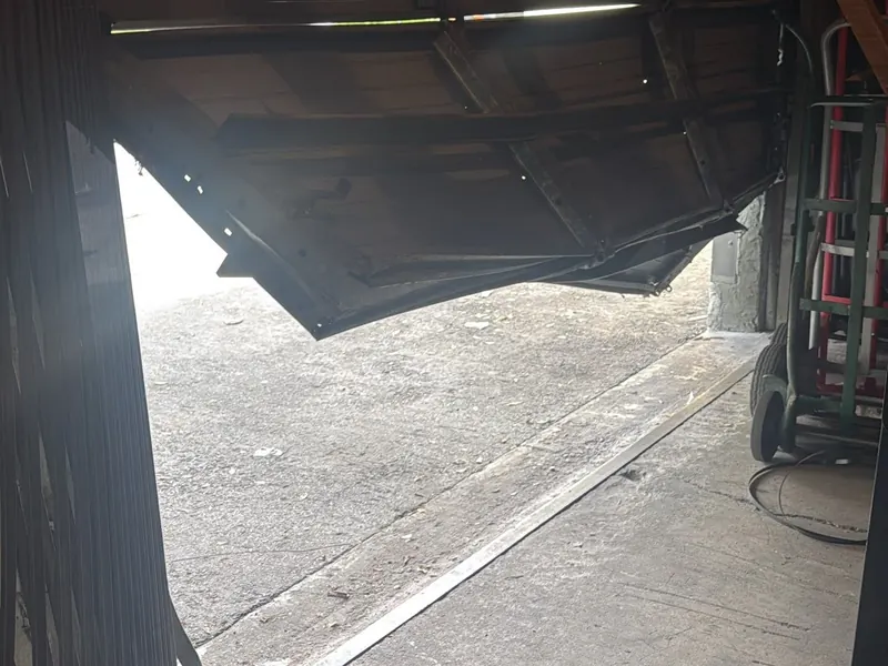 Sagging commercial sectional door panel before repair