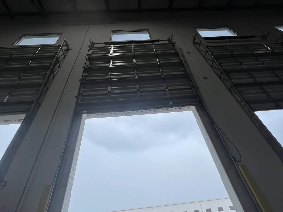 Looking up the inside face of a tall glazed commercial door standing open to the sky