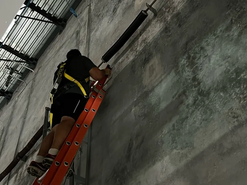 Technician on a ladder installing a torsion shaft on a commercial door