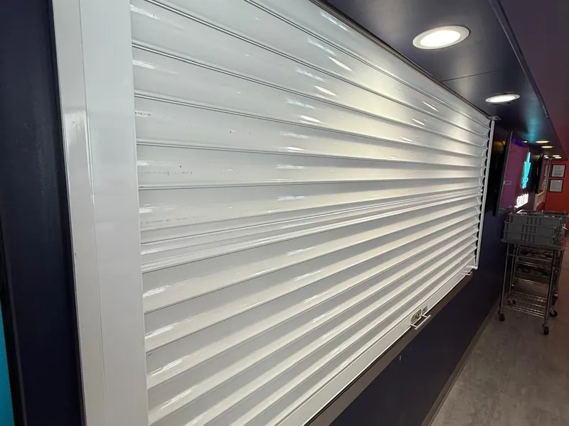 White rolling counter shutter closed over a service opening inside a store