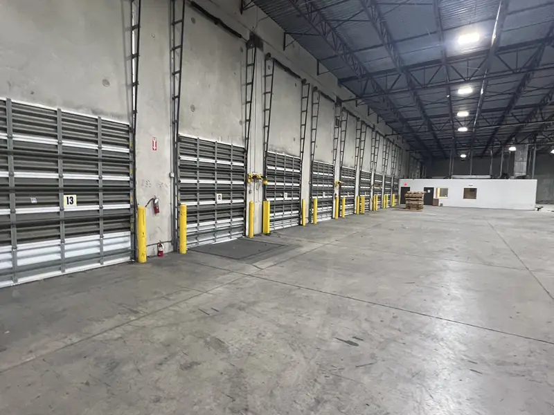 A row of steel dock doors along the inside wall of a warehouse