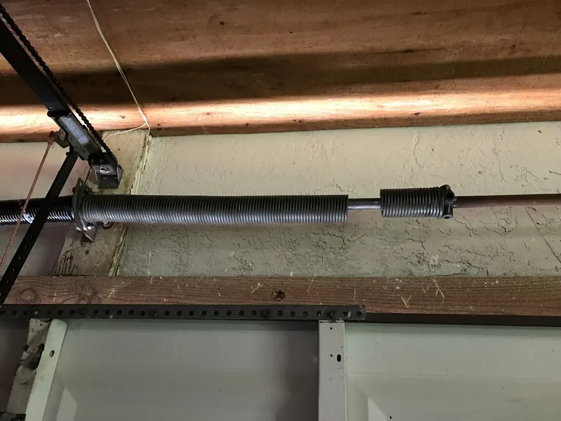 Extension spring installed along wood framing in a garage