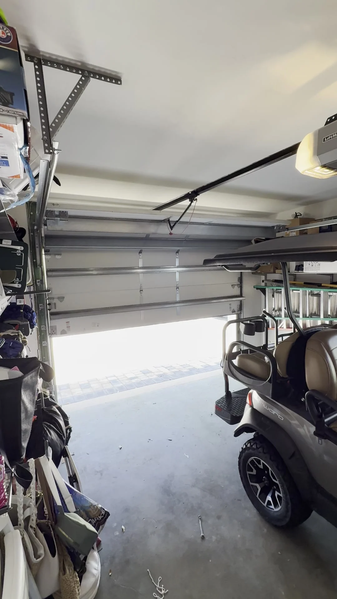 Garage door open onto the driveway with the opener rail and trolley overhead