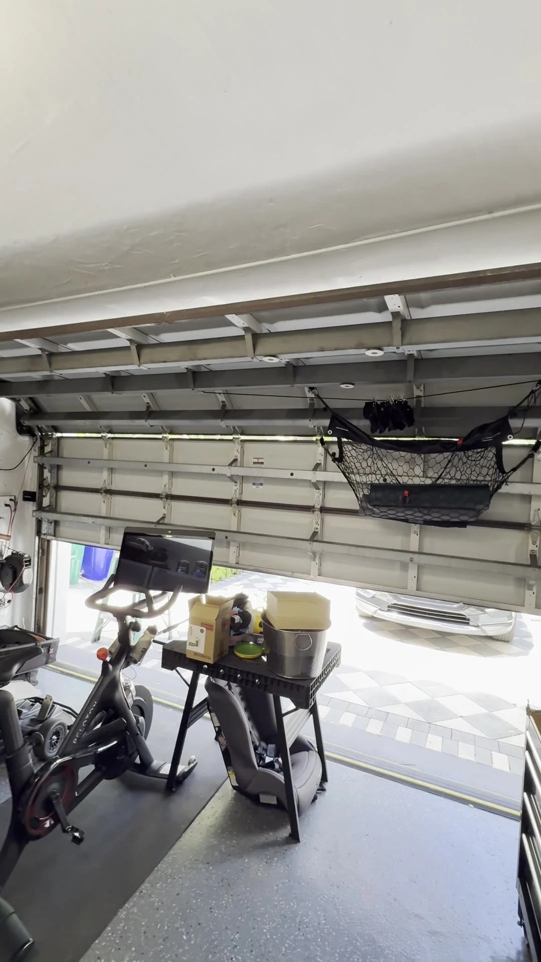 Residential garage interior with the opener overhead and the door open to the drive