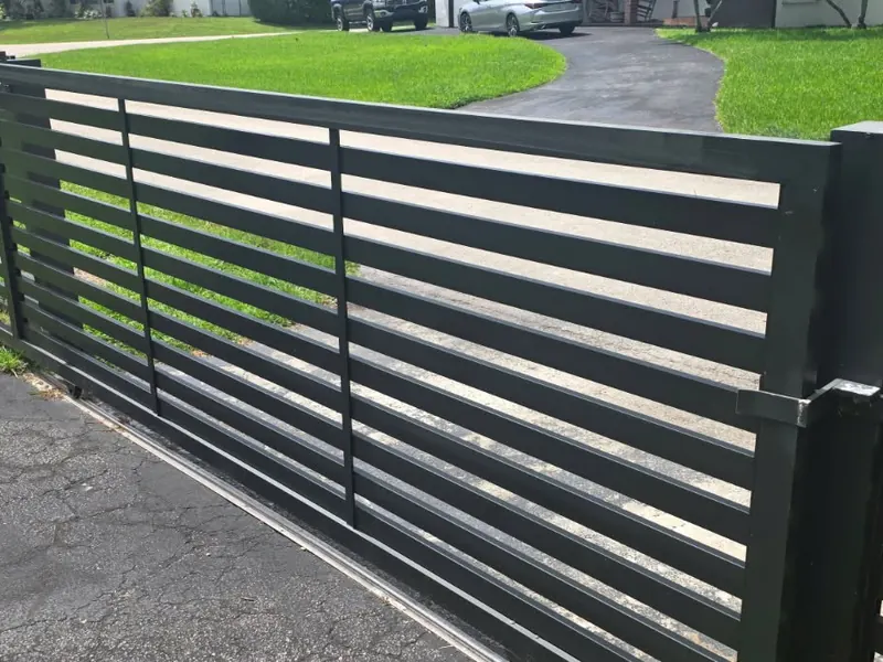 Black horizontal slat sliding gate across a driveway