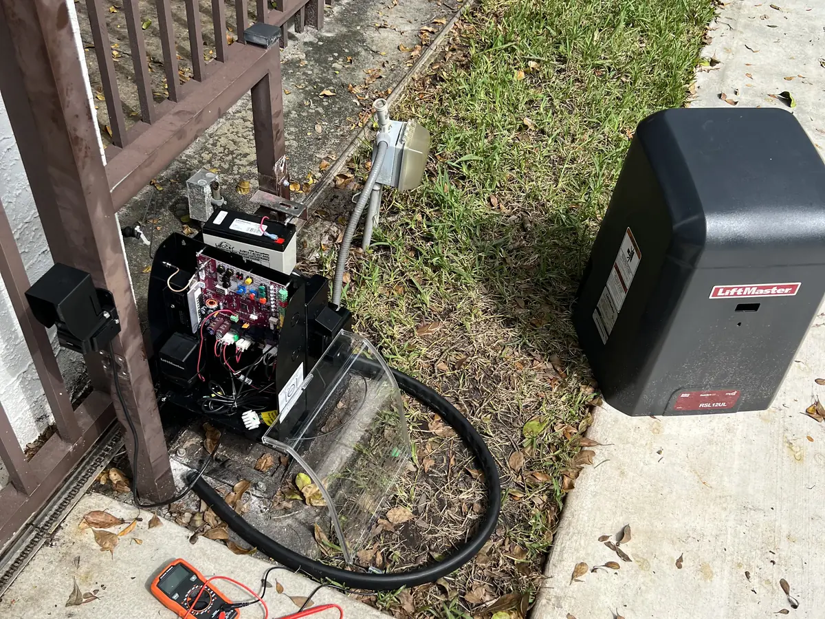 LiftMaster gate operator beside an iron fence with a multimeter on the ground mid diagnostic