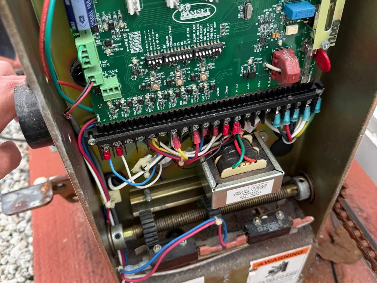 Gate operator control board wired up inside its cabinet, terminal strip and loop inputs running along the lower edge